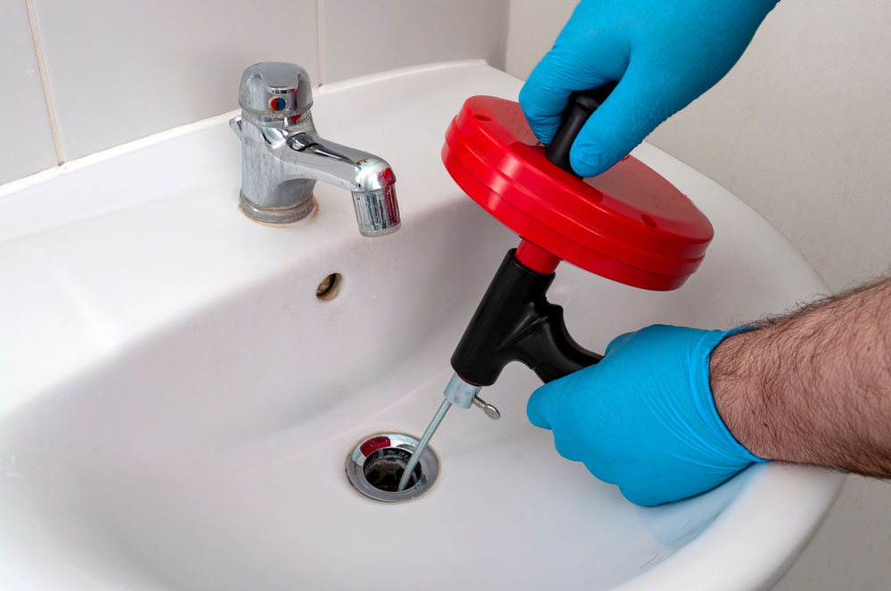 homeowner holding a drain snake tool